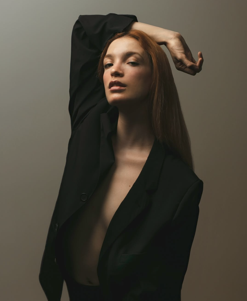 Editorial portrait of a red-haired model in a black blazer